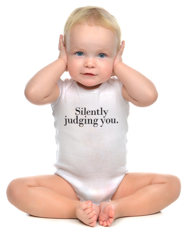 A baby wearing wrybaby's white cotton funny onesie with 'Silently Judging You' printed on the front in a nice design