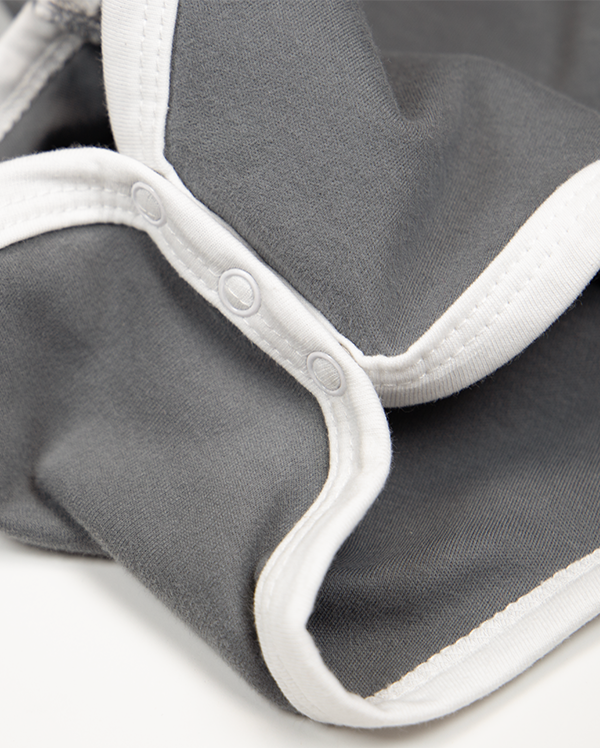 Detail of wrybaby's funny 'Expensive AF' onesie showing the baby bodysuit's white cotton leg trim.