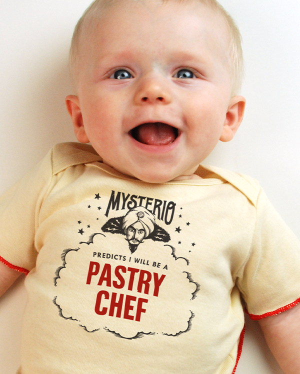 A baby wearing wrybaby's funny fortune teller t-shirt that says 'Mysterio Predicts I will be a Pastry Chef'